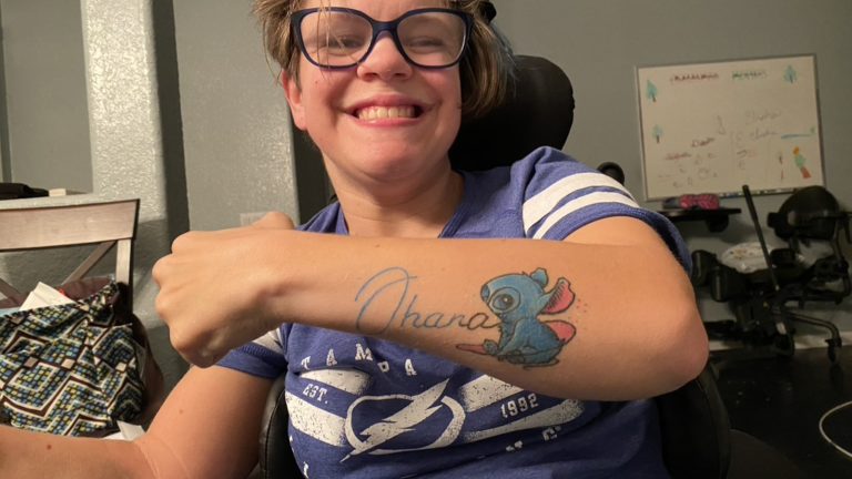 A photo of Carson with showing a tattoo with Ohana and Disney's Stitch